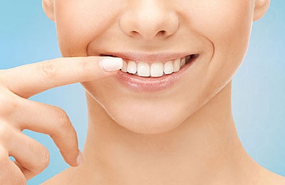 אישה מחייכת והאצבע שלה על אחת השיניים