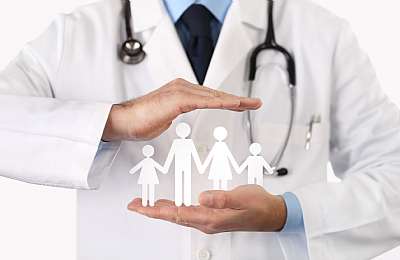 רופא מחזיק משפחה עשויה מנייר בשני ידיו